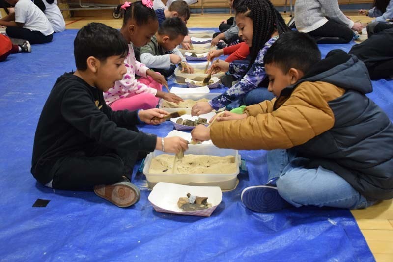 Students digging up fossils in the gym