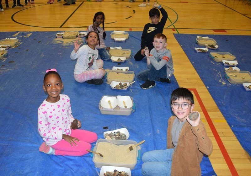 Students digging up fossils in the gym