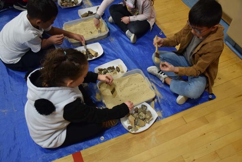 Students digging up fossils in the gym