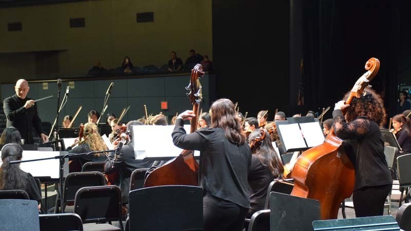 An orchestra performing while a conductor leads them