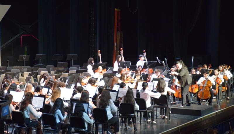 An orchestra performing while a conductor leads them