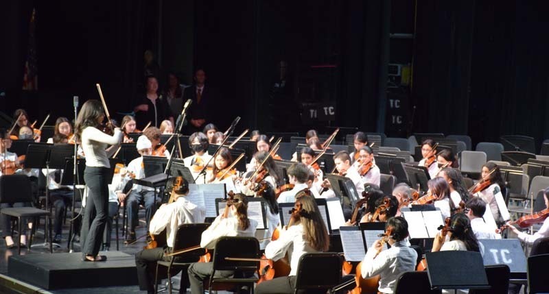 An orchestra performing while a conductor leads them