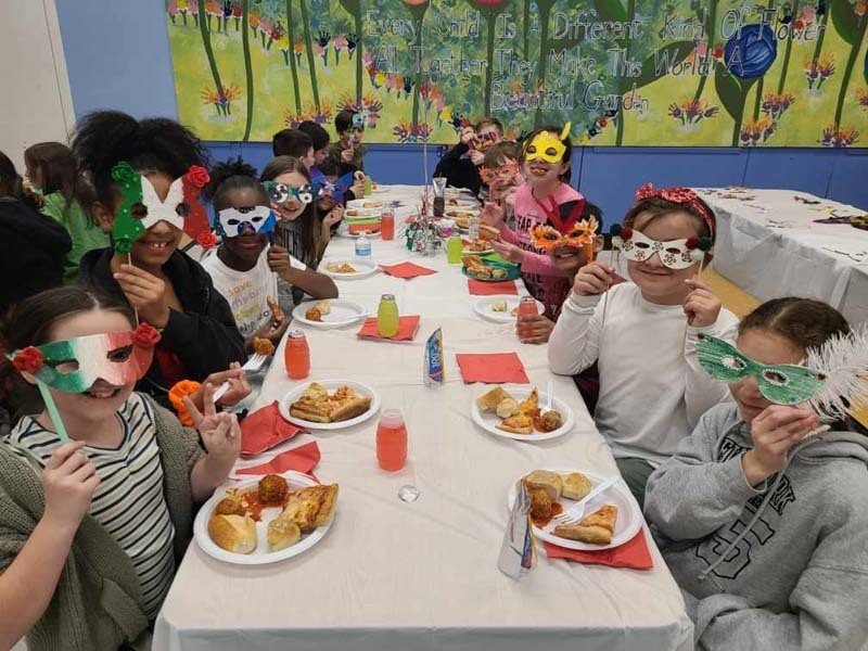 Students sitting at a table full of food nd wearing masks