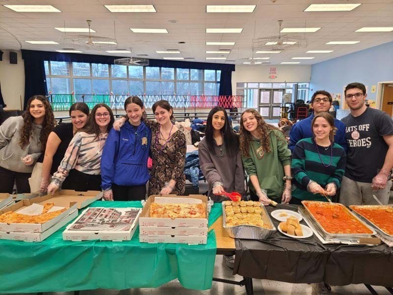 People standing behind a table full of food