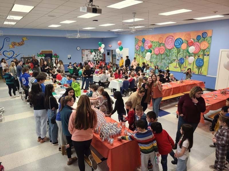 People milling around a large room full of tables and food