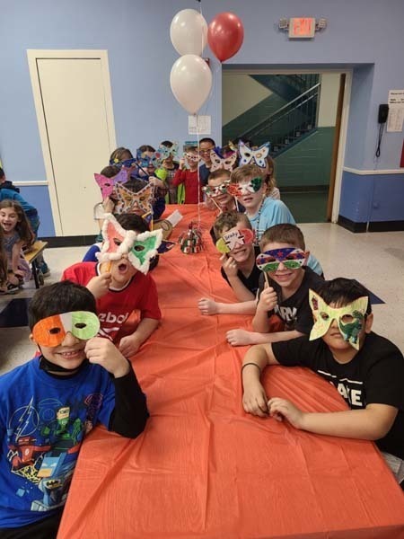 Students sitting at a table full of food nd wearing masks