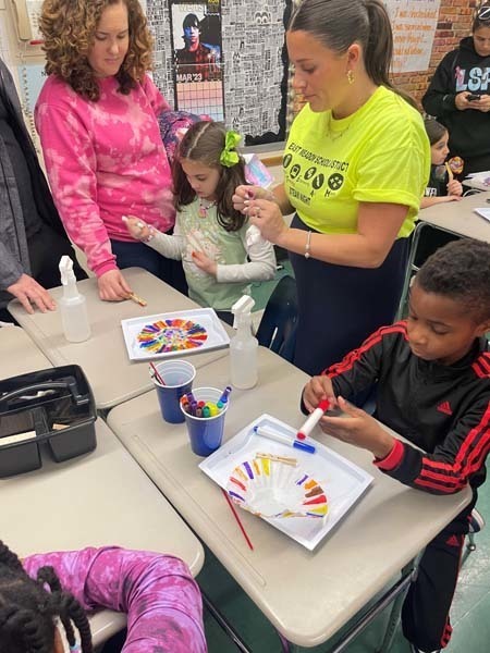 Adults helping two students color